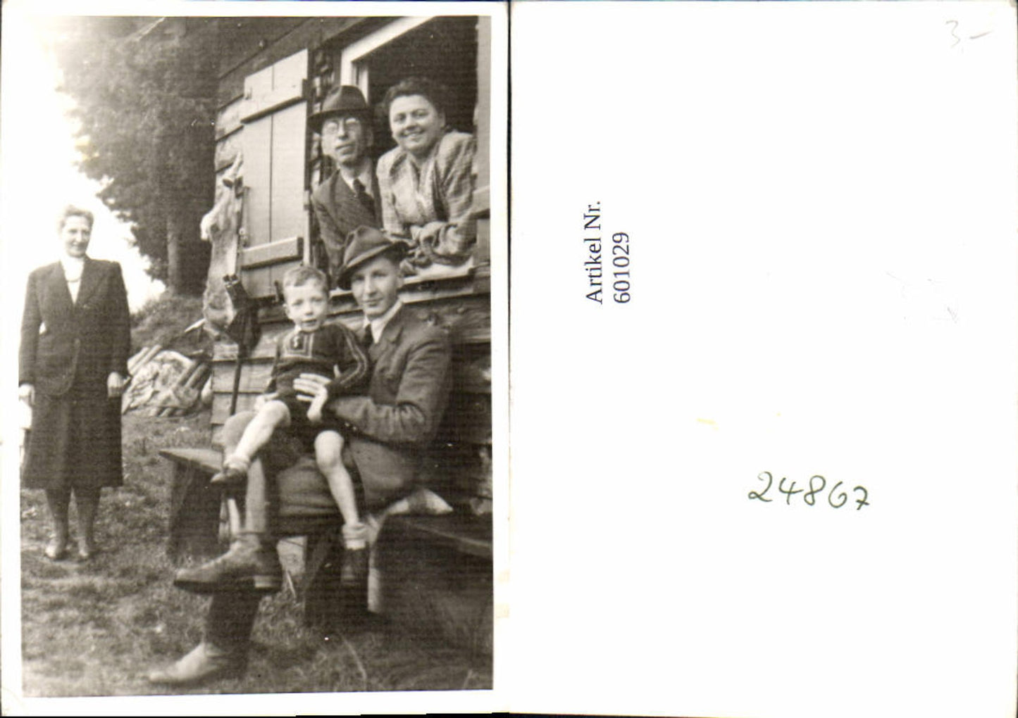 601029, Photo of men, women and child in a cabin, hunting, hare hanging in a window