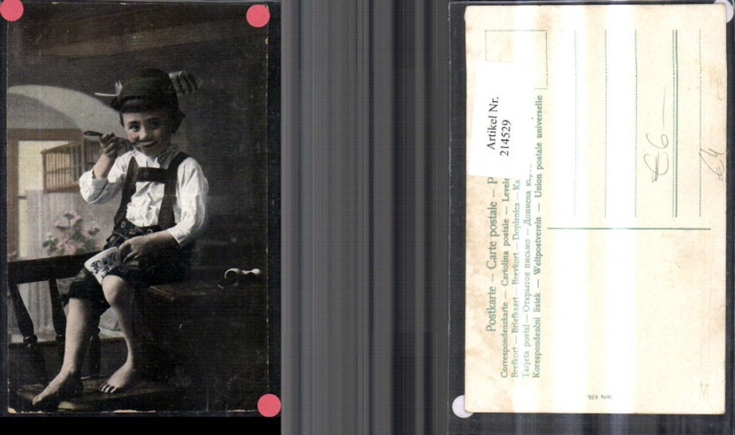 214529,Kind Bub i. Tracht Hut Federhut m. Tasse u. Löffel a. Tisch sitzend